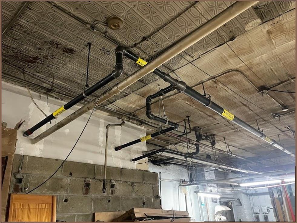 Cast-iron drain and vent lines installed by Duncan Family Plumbing in a commercial ceiling