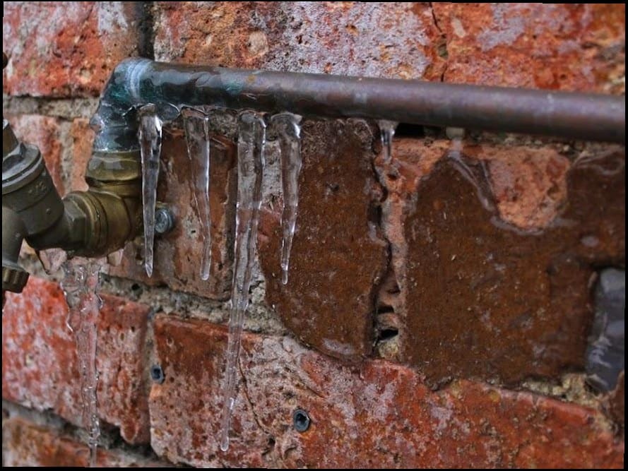 Frozen outdoor pipe with icicles on brick — the kind of plumbing emergency Duncan Family Plumbing responds to 24/7 in Bucks County, PA