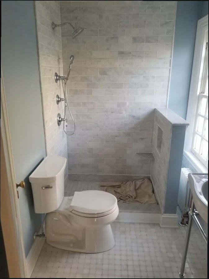 Marble tile open shower with half-wall installed by Duncan Family Plumbing
